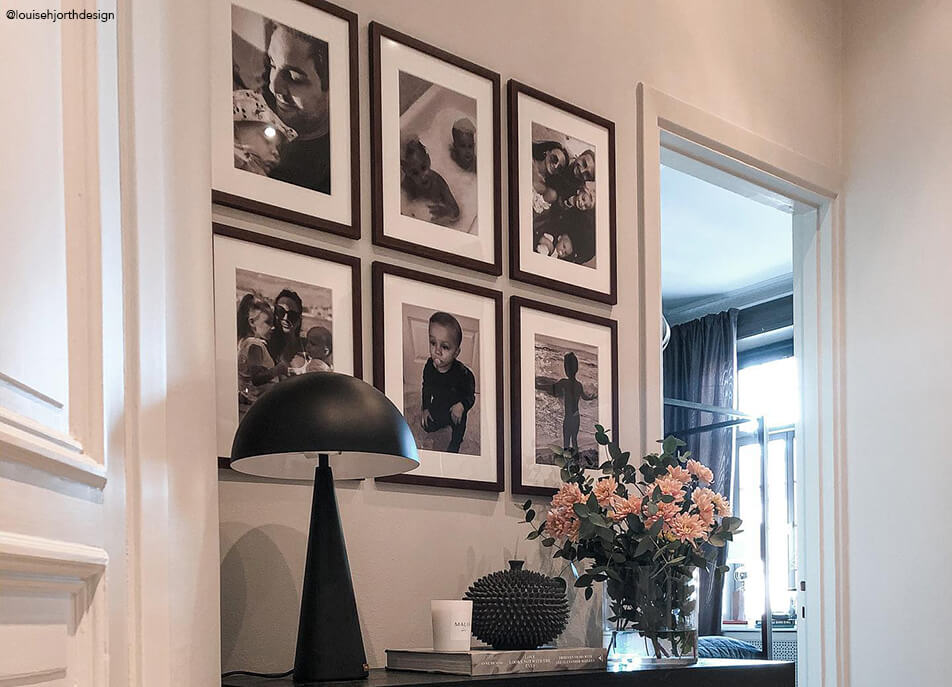 Mur de photos dans hall, photos en noir et blanc dans cadres foncés en bois